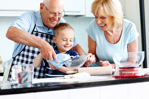 Senior couple and small kid preparing food in the kitchen
